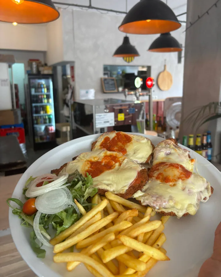 Plato con milanesas gratinadas con tomate y queso, patatas fritas y ensalada